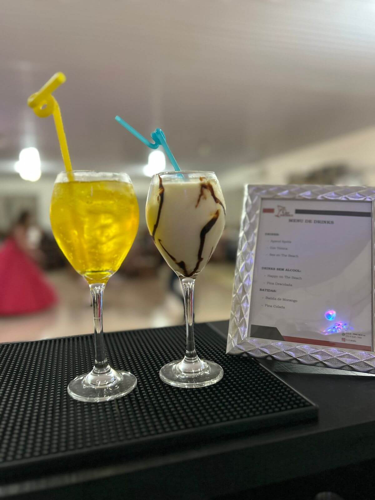 Duas taças de drinks sobre o balcão ao lado do cardápio, em um evento do G10 Drinks