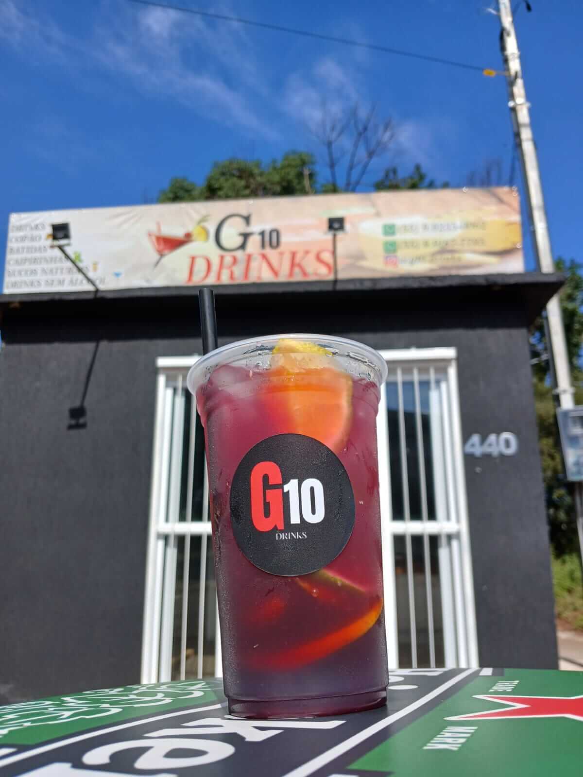 Fachada do G10 Drinks com um copo de Tinto de Verano em primeiro plano