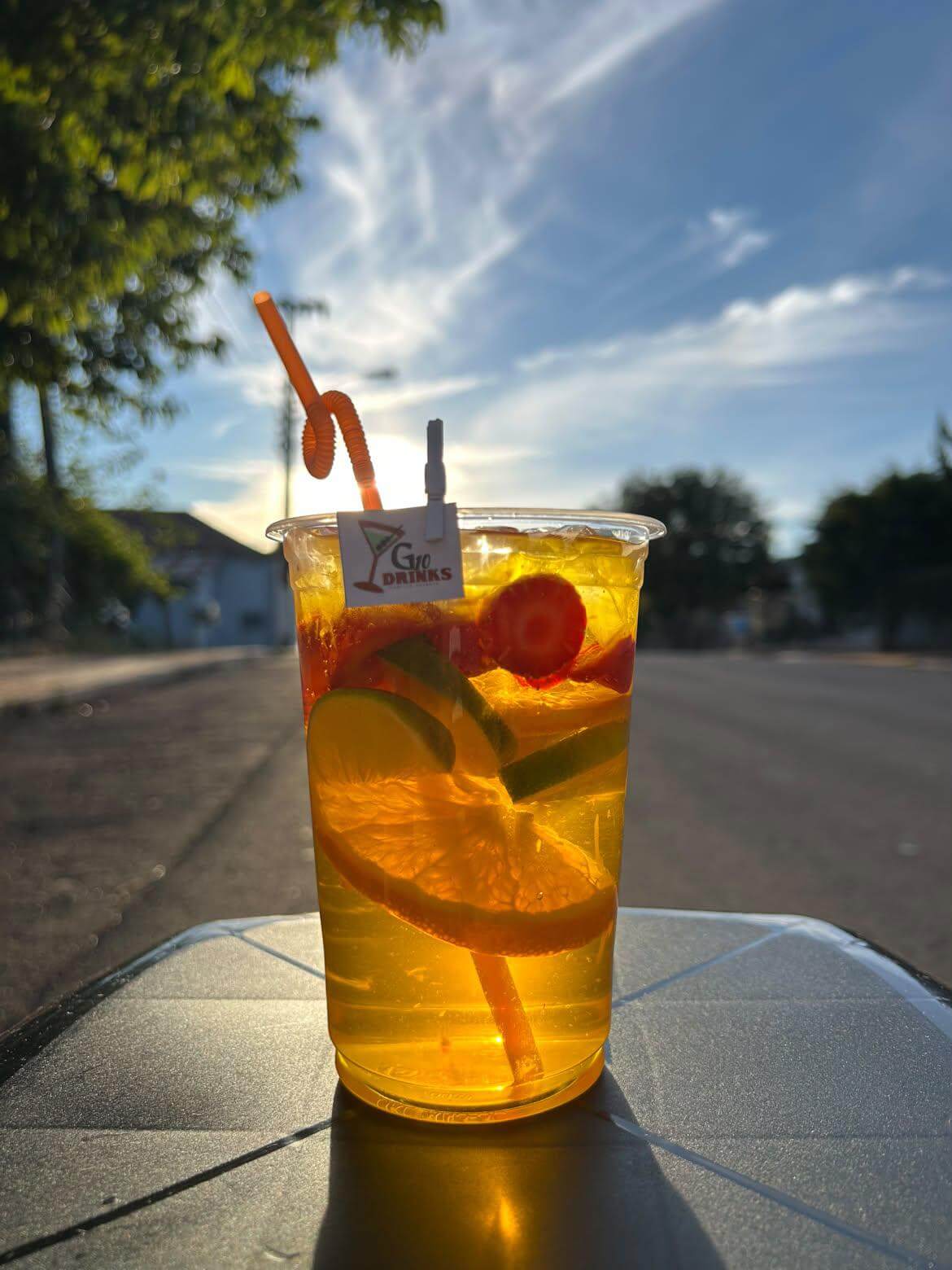 Copo de Gin Tropical com laranja e limão ao pôr do sol